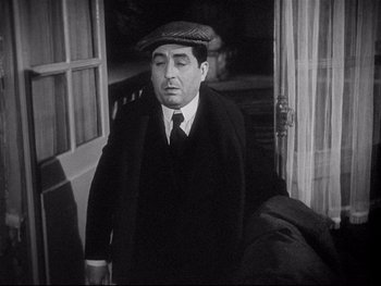 Movie still from “The Rules of the Game” (1939), directed by Jean Renoir – A man wearing a hat and a suit walking through a door way; Medium shot, High angle