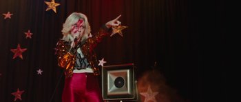 Movie still from “The Runaways” (2010), directed by Floria Sigismondi – A woman in a red and gold outfit holding up a star; Medium shot, Low angle