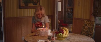 Movie still from “The Runaways” (2010), directed by Floria Sigismondi – A woman sitting in front of a birthday cake; Medium shot, Over the shoulder angle