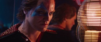 Movie still from “The Runaways” (2010), directed by Floria Sigismondi – A man with blue and red face paint looking into the camera; Close Up shot, Over the shoulder angle