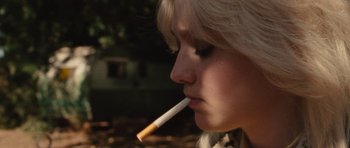 Movie still from “The Runaways” (2010), directed by Floria Sigismondi – A woman is smoking a cigarette in a park; Close Up shot, Over the shoulder angle