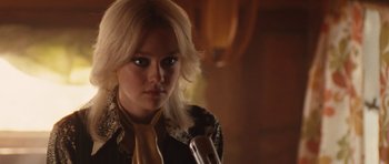 Movie still from “The Runaways” (2010), directed by Floria Sigismondi – A woman with blonde hair and a yellow neck tie holding a wine glass; Close Up shot, Over the shoulder angle