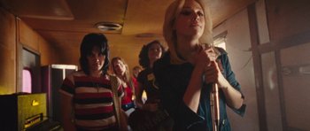 Movie still from “The Runaways” (2010), directed by Floria Sigismondi – A group of young women standing next to each other on a bus; Medium shot, Low angle
