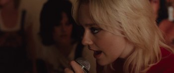 Movie still from “The Runaways” (2010), directed by Floria Sigismondi – A woman holding a microphone up to her mouth; Close Up shot, Over the shoulder angle