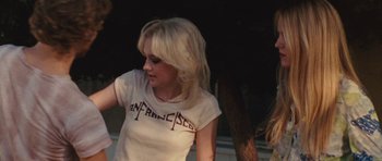 Movie still from “The Runaways” (2010), directed by Floria Sigismondi – A woman with blond hair wearing a san fransisco t - shirt; Medium shot, Over the shoulder angle