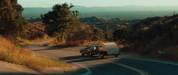 Movie still from “The Runaways” (2010), directed by Floria Sigismondi – A truck pulling a trailer on the side of the road; Extreme Wide shot, High angle