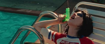 Movie still from “The Runaways” (2010), directed by Floria Sigismondi – A young child drinking a green drink from a straw; Medium shot, Overhead angle