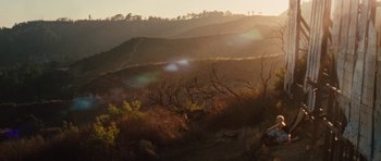 Movie still from “The Runaways” (2010), directed by Floria Sigismondi – The sun is setting over a hilly area with trees; Extreme Wide shot, High angle