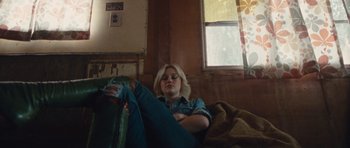 Movie still from “The Runaways” (2010), directed by Floria Sigismondi – A woman sitting on a bed with her legs crossed; Medium shot, High angle