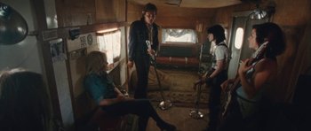 Movie still from “The Runaways” (2010), directed by Floria Sigismondi – A group of young people standing around in a room; Wide shot, High angle