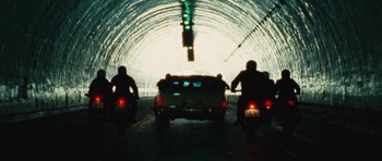 Movie still from “The Runaways” (2010), directed by Floria Sigismondi – Three people on motor scooters driving through a tunnel; Wide shot, High angle