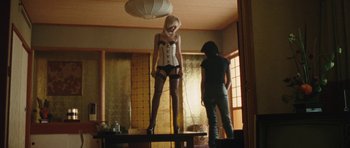 Movie still from “The Runaways” (2010), directed by Floria Sigismondi – A woman standing on top of a table next to another woman; Wide shot, Low angle