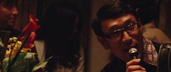 Movie still from “The Runaways” (2010), directed by Floria Sigismondi – A man wearing glasses is looking at a woman; Close Up shot, Over the shoulder angle