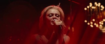Movie still from “The Runaways” (2010), directed by Floria Sigismondi – A woman is singing into a microphone in the dark; Close Up shot, Low angle