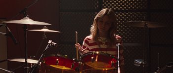 Movie still from “The Runaways” (2010), directed by Floria Sigismondi – A woman is playing drums in a recording studio; Medium shot, High angle