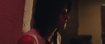 Movie still from “The Runaways” (2010), directed by Floria Sigismondi – A woman wearing a necklace looking to her left; Close Up shot, Low angle