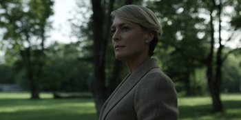 Movie still from “House of Cards” (2013), created by Beau Willimon – A woman is standing in the grass near a tree; Close Up shot, Low angle