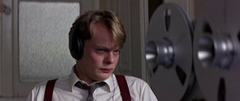 Movie still from “The Russia House” (1990), directed by Fred Schepisi – A young man wearing headphones and a white shirt; Close Up shot, High angle