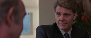 Movie still from “The Russia House” (1990), directed by Fred Schepisi – A person wearing a suit and tie; Close Up shot, Over the shoulder angle