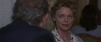 Movie still from “The Russia House” (1990), directed by Fred Schepisi – A woman looking into a mirror while a man looks on; Close Up shot, Over the shoulder angle