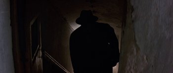 Movie still from “The Russia House” (1990), directed by Fred Schepisi – A man wearing a hat and a trench coat in the dark; Medium shot, Low angle