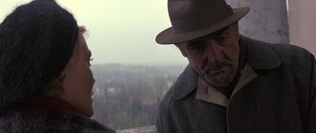 Movie still from “The Russia House” (1990), directed by Fred Schepisi – A man in a hat talking to a woman in a gray coat; Close Up shot, Over the shoulder angle