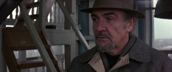 Movie still from “The Russia House” (1990), directed by Fred Schepisi – An older man wearing a hat and a coat; Close Up shot, Over the shoulder angle