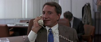 Movie still from “The Russia House” (1990), directed by Fred Schepisi – A man in a suit and tie talking on a phone; Close Up shot, Low angle