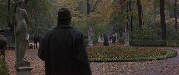 Movie still from “The Russia House” (1990), directed by Fred Schepisi – A man in a hat and a coat walking in a park; Wide shot, Over the shoulder angle