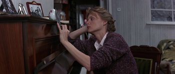Movie still from “The Russia House” (1990), directed by Fred Schepisi – A woman leaning against a piano looking at a mirror; Medium shot, Low angle