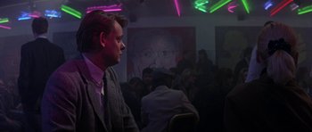 Movie still from “The Russia House” (1990), directed by Fred Schepisi – A man in a suit and tie in front of a painting; Medium shot, Over the shoulder angle