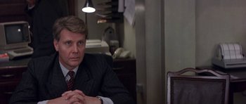 Movie still from “The Russia House” (1990), directed by Fred Schepisi – A man in a suit and tie sitting at a table; Close Up shot, Over the shoulder angle