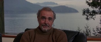 Movie still from “The Russia House” (1990), directed by Fred Schepisi – An older man sitting on a couch in front of a body of water; Close Up shot, Over the shoulder angle