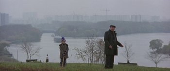 Movie still from “The Russia House” (1990), directed by Fred Schepisi – A man standing next to a child in a field; Wide shot, High angle