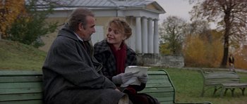 Movie still from “The Russia House” (1990), directed by Fred Schepisi – An older man sitting next to a woman on a park bench; Medium shot, Low angle