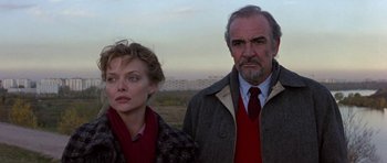 Movie still from “The Russia House” (1990), directed by Fred Schepisi – A man and a woman standing next to each other in a field; Medium shot, Low angle