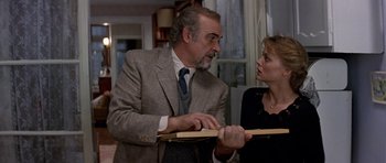 Movie still from “The Russia House” (1990), directed by Fred Schepisi – An older man in a suit talking to an older woman in a black dress; Medium shot, Over the shoulder angle