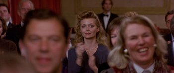 Movie still from “The Russia House” (1990), directed by Fred Schepisi – A woman in a crowd of people at an event; Close Up shot, Over the shoulder angle