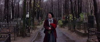 Movie still from “The Russia House” (1990), directed by Fred Schepisi – A woman holding a bouquet of roses in a wooded area; Wide shot, High angle