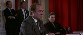 Movie still from “The Russia House” (1990), directed by Fred Schepisi – A man in a suit and tie sitting next to another man in a suit and tie; Medium shot, Low angle