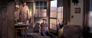 Movie still from “The Russians Are Coming the Russians Are Coming” (1966), directed by Norman Jewison – A young boy sitting on the ground in front of a window; Wide shot, Over the shoulder angle