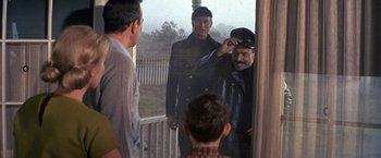 Movie still from “The Russians Are Coming the Russians Are Coming” (1966), directed by Norman Jewison – A group of men standing next to each other on a porch; Medium shot, Over the shoulder angle