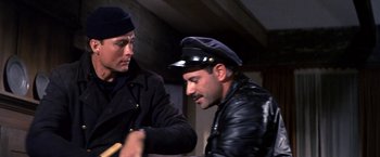Movie still from “The Russians Are Coming the Russians Are Coming” (1966), directed by Norman Jewison – A man in a leather jacket and a man in a hat; Medium shot, Over the shoulder angle