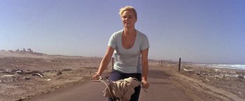Movie still from “The Russians Are Coming the Russians Are Coming” (1966), directed by Norman Jewison – A woman riding a bike down a dirt road; Medium shot, Low angle