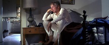 Movie still from “The Russians Are Coming the Russians Are Coming” (1966), directed by Norman Jewison – An older man sitting on a chair talking on a phone; Medium shot, Low angle