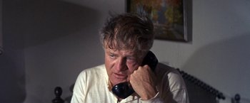 Movie still from “The Russians Are Coming the Russians Are Coming” (1966), directed by Norman Jewison – An older man talking on a phone while sitting in a room; Close Up shot, High angle