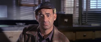 Movie still from “The Russians Are Coming the Russians Are Coming” (1966), directed by Norman Jewison – An older man wearing a hat and a jacket; Close Up shot, Over the shoulder angle