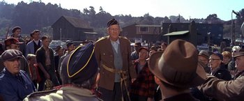 Movie still from “The Russians Are Coming the Russians Are Coming” (1966), directed by Norman Jewison – An old man in a military uniform standing in front of a group of people; Medium shot, Over the shoulder angle
