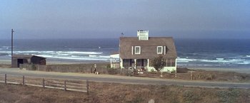 Movie still from “The Russians Are Coming the Russians Are Coming” (1966), directed by Norman Jewison – A person walking on the beach near a house; Extreme Wide shot, High angle