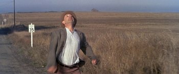 Movie still from “The Russians Are Coming the Russians Are Coming” (1966), directed by Norman Jewison – A man wearing a hat standing in the middle of an open field; Wide shot, Low angle